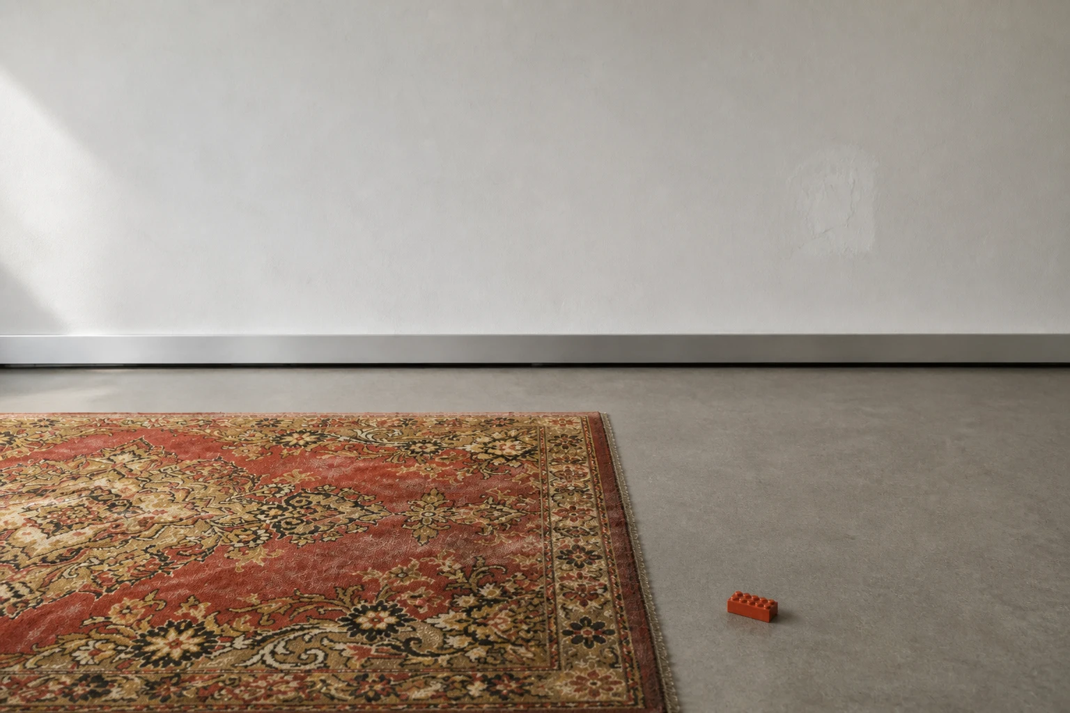 A worn Soviet carpet and one small old brick sharing a quiet Estonian room